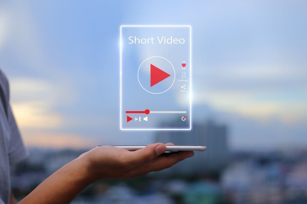 Person holding smartphone in palm of hand with video icon above it